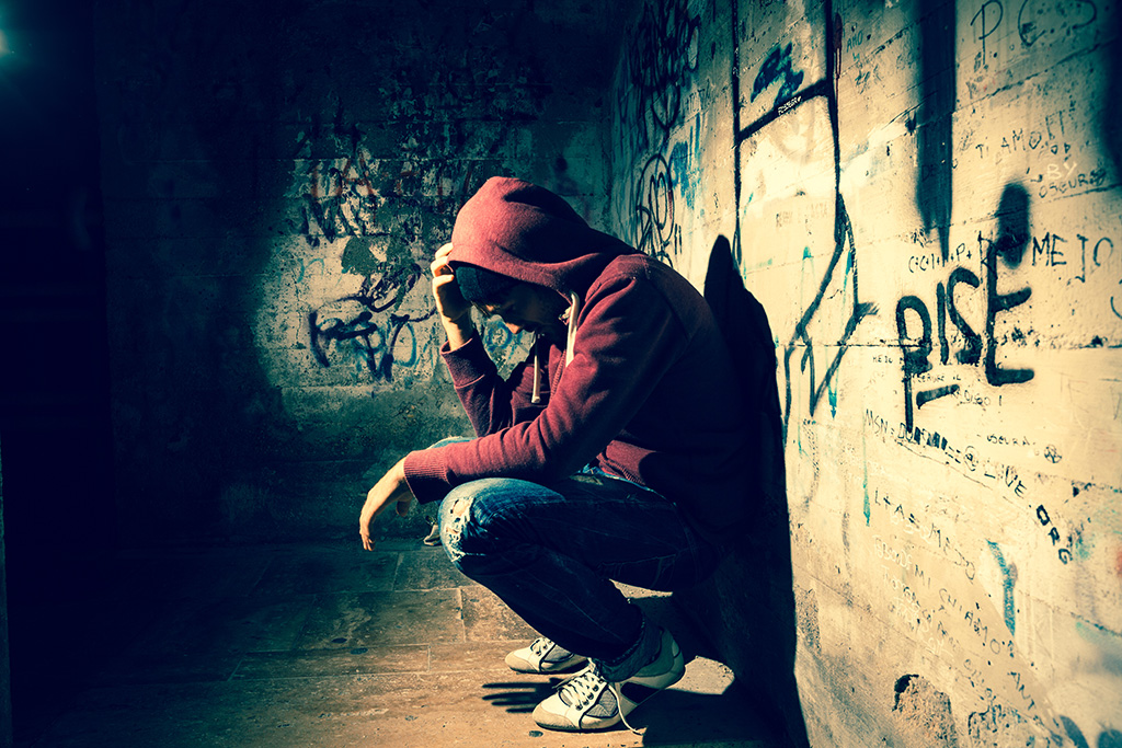 Ragazzo solo accovacciato che esprime disagio