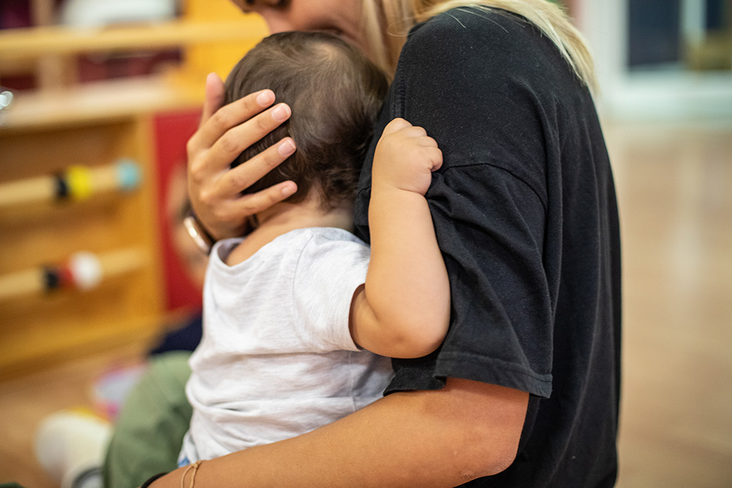 Educatrice di nido d'infanzia con in braccio un bambini